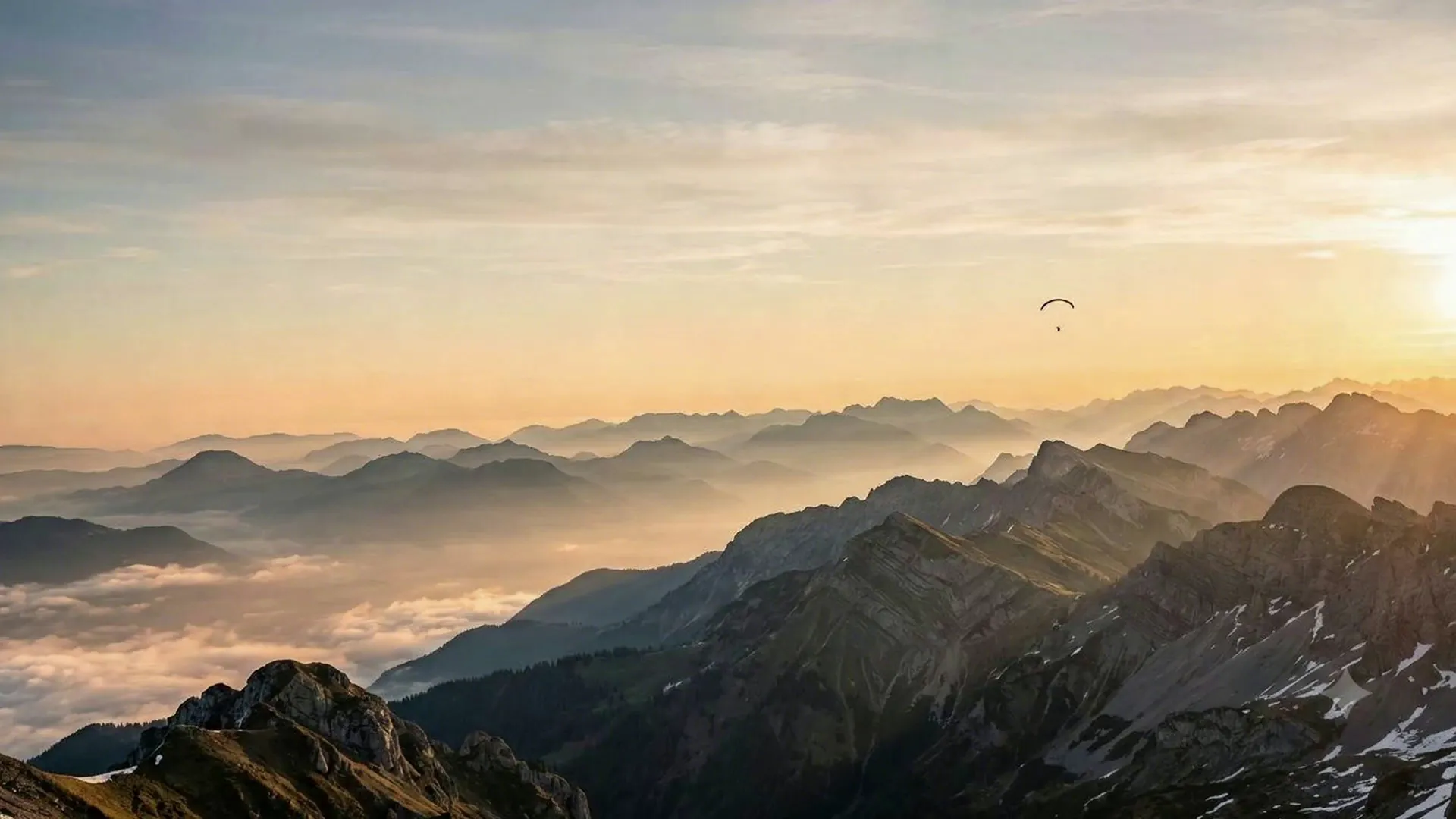 Gleitschirm im Morgenlicht über den Alpen, Wolkenmeer und Bergketten